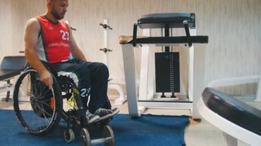 Tekerlekli sandalyede oturan adam egzersiz yaparak devre dışı ve bir dumbbell alır