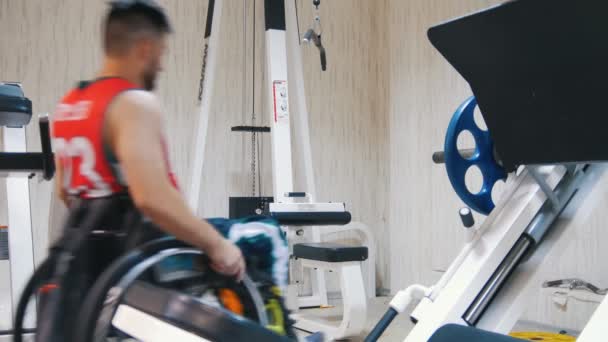 Homem com deficiência sentado na cadeira de rodas fazendo exercício enquanto treina na academia — Vídeo de Stock