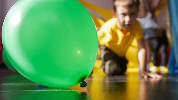 Yeşil balon ve arka planda hayran odaklanmamış çocuk — Stok fotoğraf