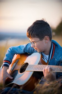 Sunset Bulvarında akustik gitar yaz alanına bakarak genç genç çocuk