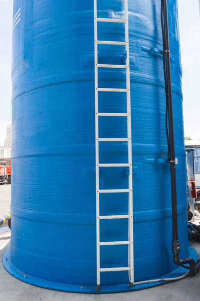 Torre de agua azul con escalera blanca y manguera negra — Foto de Stock
