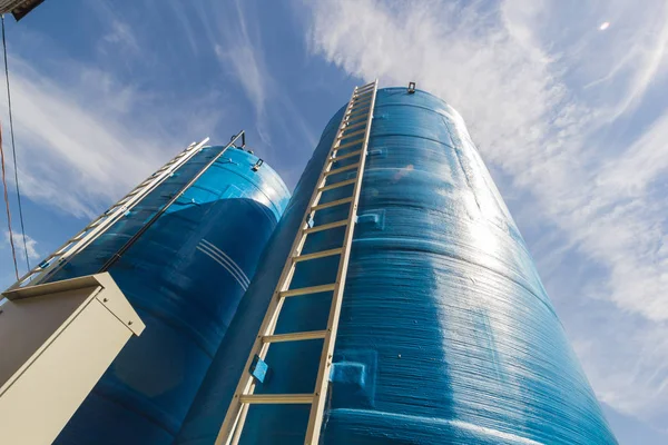 Torre de agua azul con escalera blanca y manguera negra — Foto de Stock