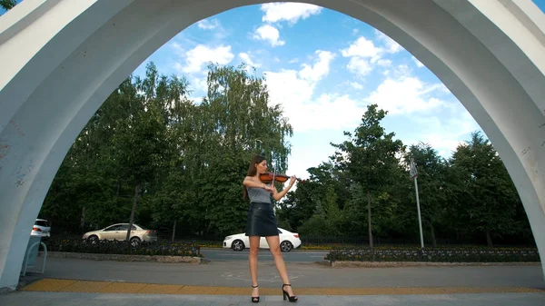 Молодая девушка играет на винтажной скрипке в парке — стоковое фото