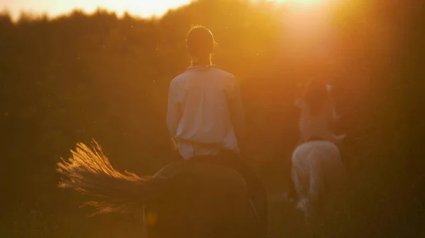 Дві молоді дівчата катаються на конях на заході сонця — стокове фото