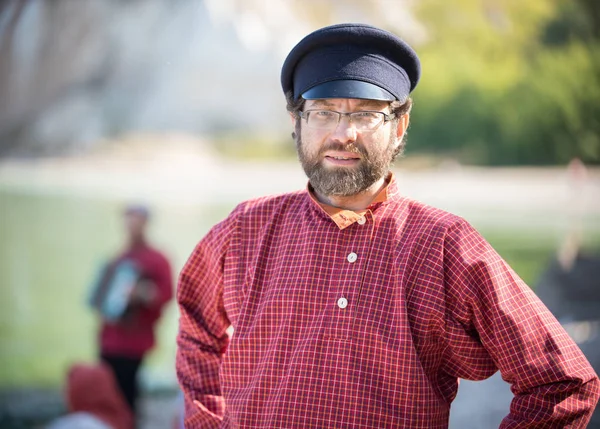 Een man in een Russisch-folk kostuum staat op een achtergrond van water en vormt voor de camera — Stockfoto