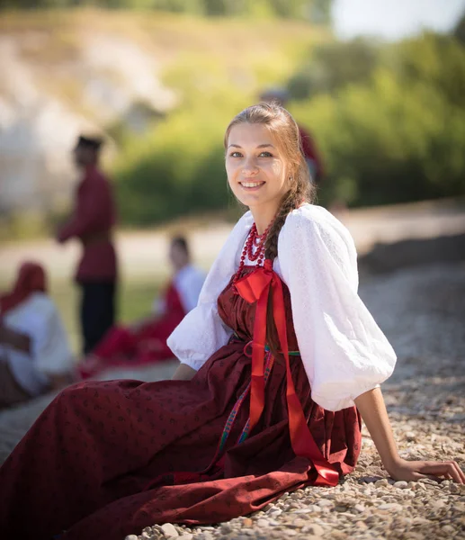 Красивая девушка в русском национальном костюме позирует перед камерой на фоне удивительного пейзажа — стоковое фото