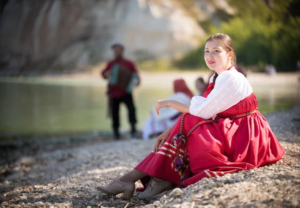 Девушка в русском национальном костюме сидит на песке на фоне удивительного пейзажа — стоковое фото