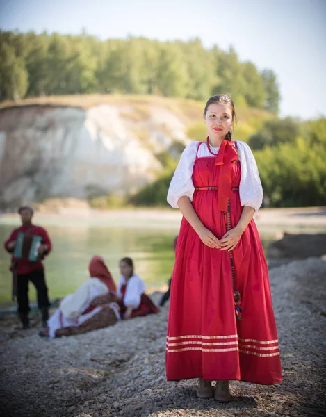Красивая девушка в красном русском национальном костюме стоит на фоне удивительного пейзажа — стоковое фото