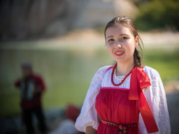 Девушка в красном русском национальном костюме стоит на фоне удивительного пейзажа крупным планом — стоковое фото