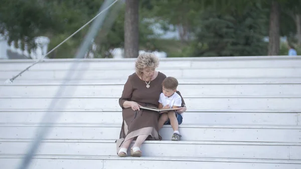 Бабушка с внуком читают вместе книгу — стоковое фото