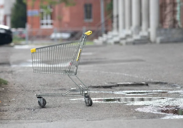 Carrinho de mercearia fica sozinho na rua no asfalto molhado — Fotografia de Stock