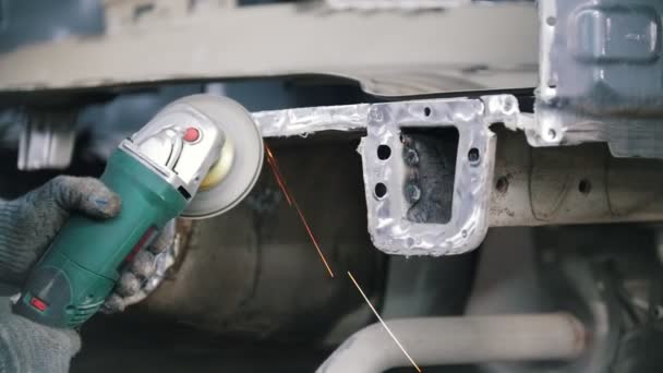 De mechanica hand in de handschoen maalt de auto-onderdeel met een grinder — Stockvideo