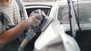 Tamirci adam araba vücut bir öğütücü ile biler ve arabanın kapısını kapatır