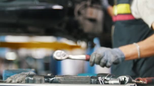 De monteur zet de hulpprogramma's op de tabel in de auto reparatiewerkplaats — Stockvideo