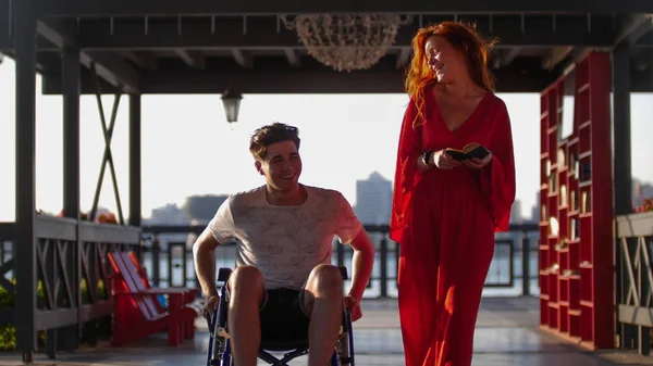 Красива червона дівчина Rolls guy в a інвалідний візок на the Promenade in the Evening — стокове фото