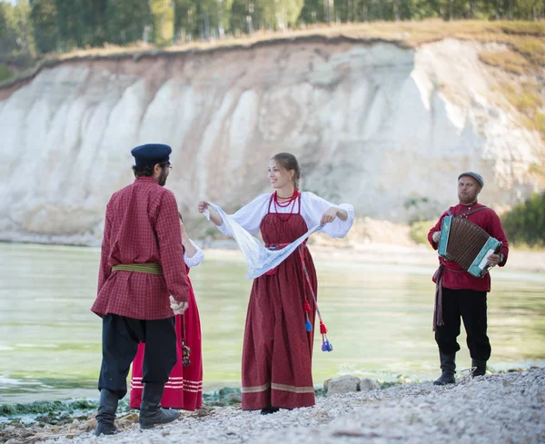 Группа молодых людей в русских национальных костюмах на фоне реки — стоковое фото