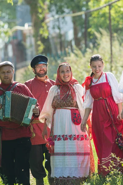 Группа мужчин и женщин в русских народных костюмах на природе. Празднование. Деревня — стоковое фото