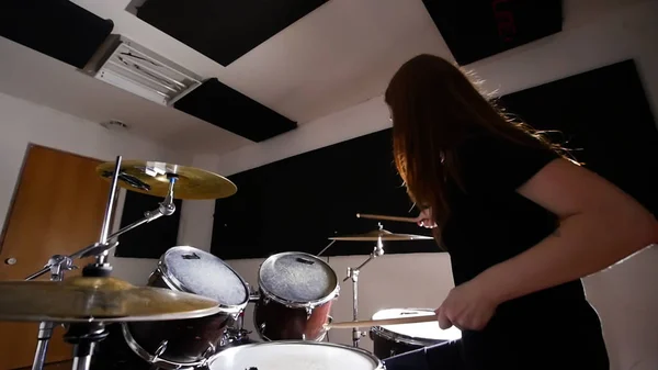 Jonge meisje uitoefenen op een drum set in een muziekstudio. Uitzicht vanaf de onderkant — Stockfoto