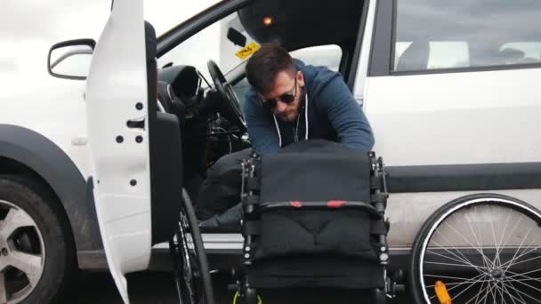 Disabled man in a car put together his wheelchair and picks it up in a car — Stock Video
