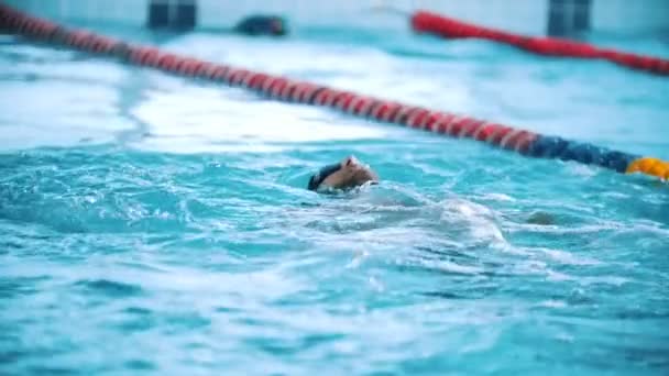 Un handicapé nage sur le dos dans une piscine. Au ralenti. Le coup de papillon . — Video