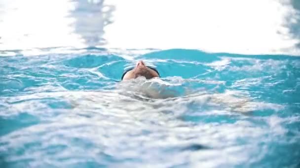 Инвалид плавает на спине в бассейне. Удар бабочки. Медленное движение — стоковое видео