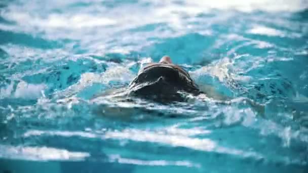 El hombre discapacitado nada en la espalda en una piscina hacia la cámara. Primer plano. Movimiento lento — Vídeos de Stock