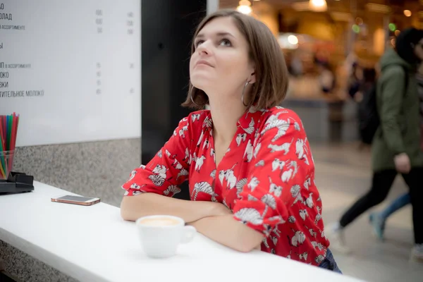 Vacker flicka med kort hår sitter tonföljd på ett kafé — Stockfoto