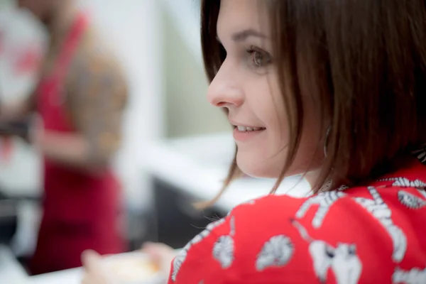 Den unga flickan i röd skjorta ser bort och ler mot bakgrund av kaffehuset — Stockfoto