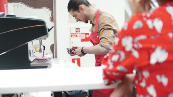 Girl in red shirt sits in a coffee shop and waits for her order — Stock Video