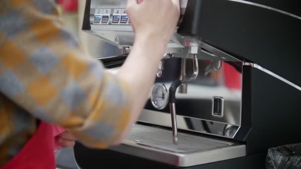 Barista limpia una tubería de una máquina de café en una cafetería . — Vídeos de Stock