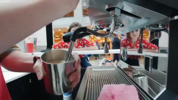 Barista μαστίγια γάλα σε μια μηχανή του καφέ, πελάτη, εξετάζοντας το θέμα — Αρχείο Βίντεο