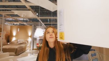 Güzel kız bir dolabı açar ve bunu inceliyor
