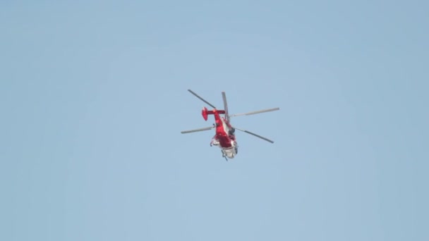 Un helicóptero rojo vuela en el horizonte en un cielo despejado — Vídeos de Stock