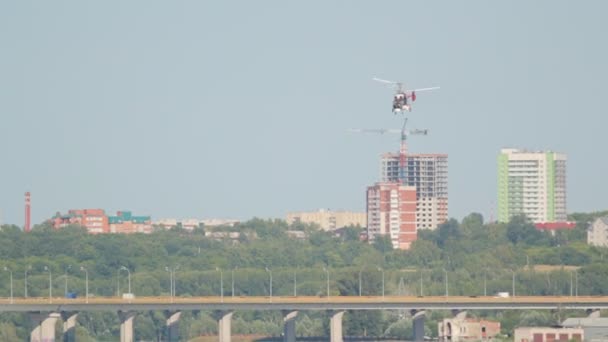 Λευκό ελικόπτερο που πετούν πάνω από ένα ποτάμι το φόντο της πόλης — Αρχείο Βίντεο