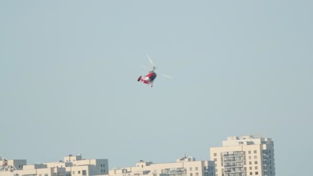 Helicóptero rojo-blanco se vuelve contra un parque de la ciudad con una rueda de hurón — Vídeo de stock