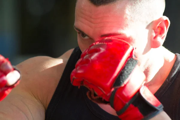 Μυϊκή bodybuilder στον Γάντια προπόνησης χτυπάει ένα σάκο ζουμπάρισμα — Φωτογραφία Αρχείου