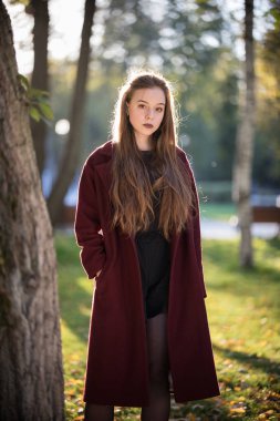 Koyu ruj ayakta parkta güzel kızla. Şarap rengi ceket, sonbahar