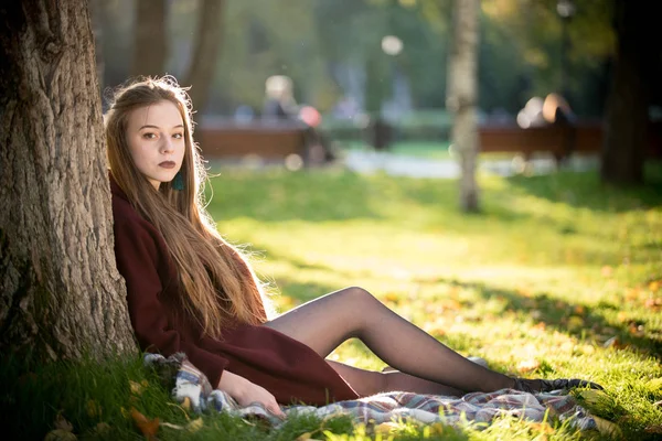 Красивая девушка с темной помадой сидит в парке . — стоковое фото