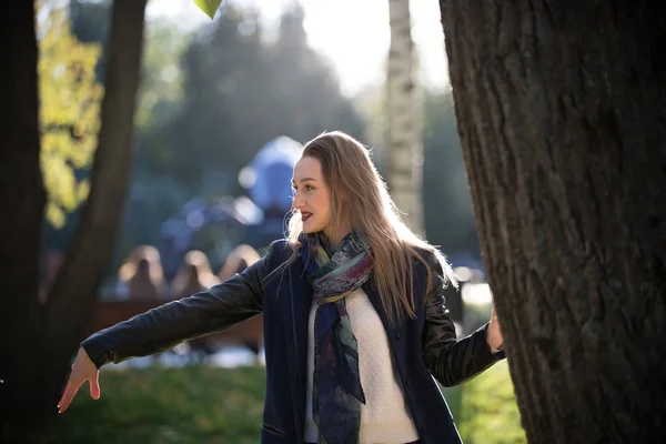 Krásná dívka v kabátě vedle strom na podzim sunny park — Stock fotografie