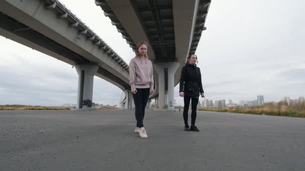 Acrobatic meninas pulando em uma divisão em direção à câmera no fundo da ponte — Vídeo de Stock