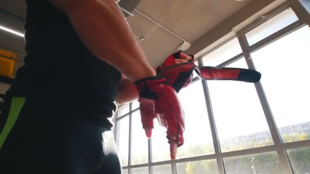 Homme musclé met ses gants de boxe à côté d'un sac de boxe — Video
