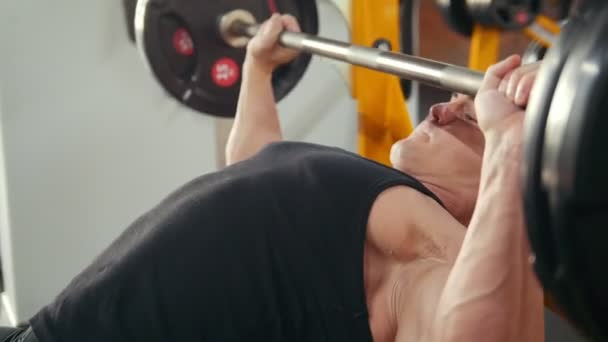 Culturista realizando ejercicio de presión de barra inclinada en un banco en el gimnasio. De cerca. — Vídeo de stock