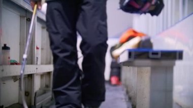 İçin çevresinde yürüyüş paten hokeyi oyuncusu yerine hokey Stadyumu ve kaskını bankta koyarak oyuncularına