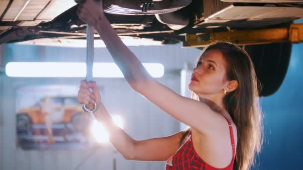 Sexy mechanic girl fixing the car with a spanner — Stock Video