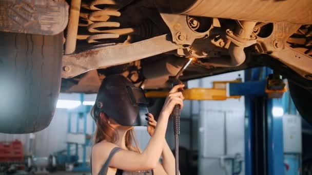 Sexy dívka mechanik opravuje auto s svařování a sundá helmu — Stock video