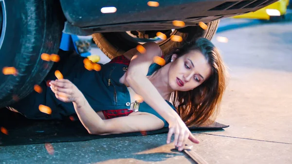 Sexy meccanico ragazza sdraiata sotto l'auto e raggiungere per la chiave inglese — Foto Stock