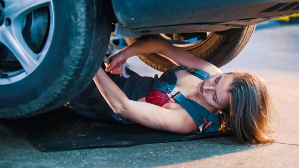 Seksi tamirci kız arabanın altında yalan ve tamir — Stok fotoğraf
