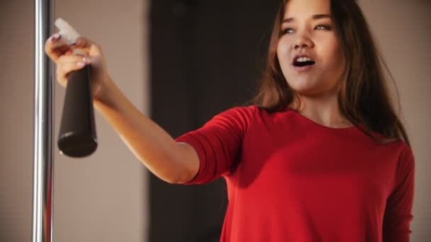 Menina sexy em vestido vermelho. A menina pulverizando água no ar e sopra em uma garrafa de spray — Vídeo de Stock