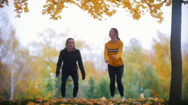 Lányok bemelegítés, edzés, a park előtt. Ugrás a helyszínen — Stock videók