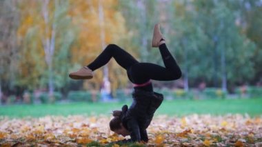 Akrobatik yapıyor kız elleri ayakları bölünmüş üzerinde durmak. Eğitim sonbahar park. Yakın çekim